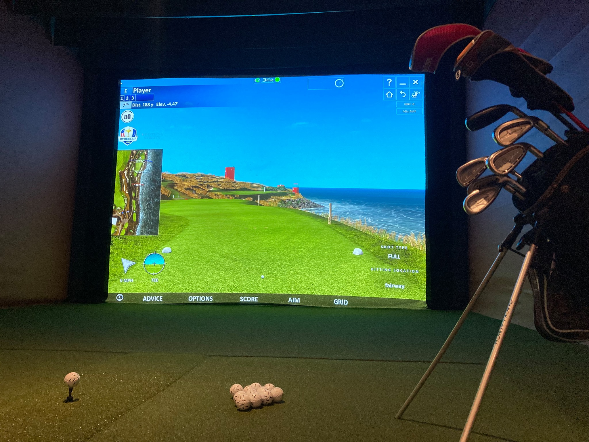 Some golf balls and clubs set up in front of a golf simulator
