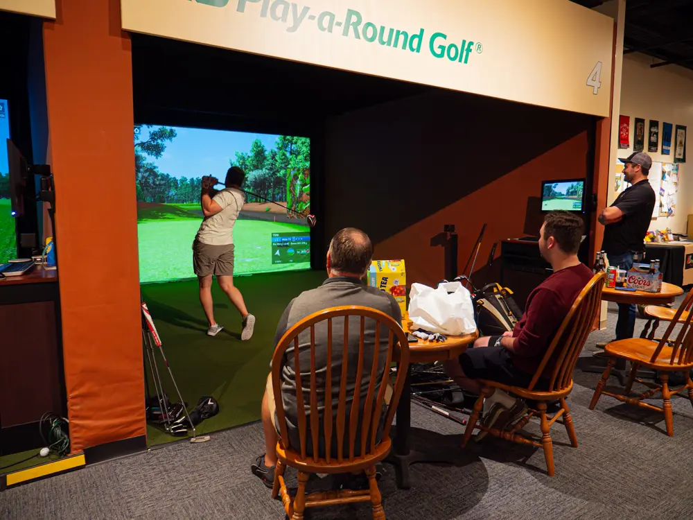  A group of friends playing golf on a golf simulator