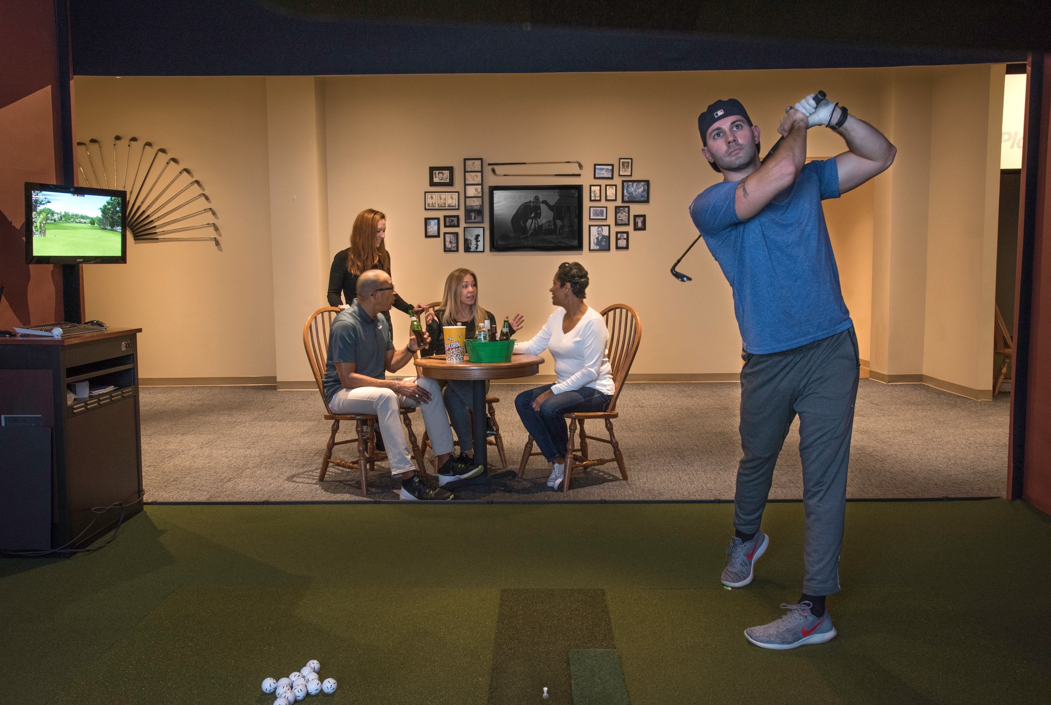 A man playing on a golf simulator a group of friends on Ardmore or Malvern, PA