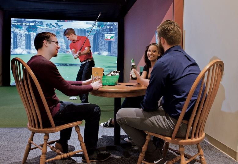 A party talking and playing simulator golf at Play-a-Round Golf 